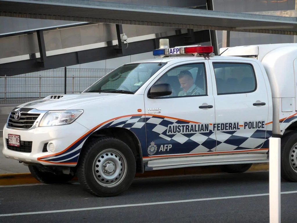A picture of two police officers sitting in an Australian federal police car.